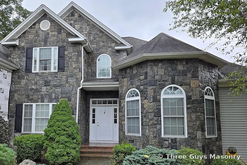 Natural stone veneer facade with arched doorway installed by Three Guys Masonry